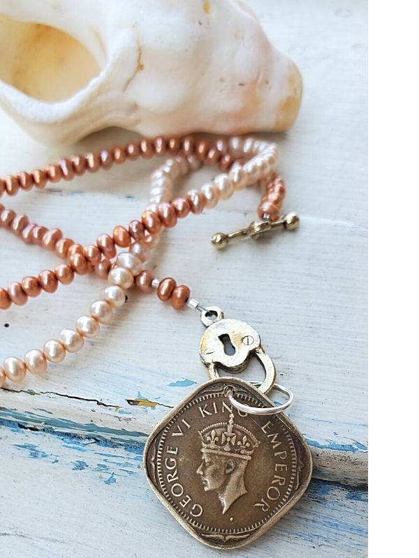 Old coin pearl necklace on a white seahell